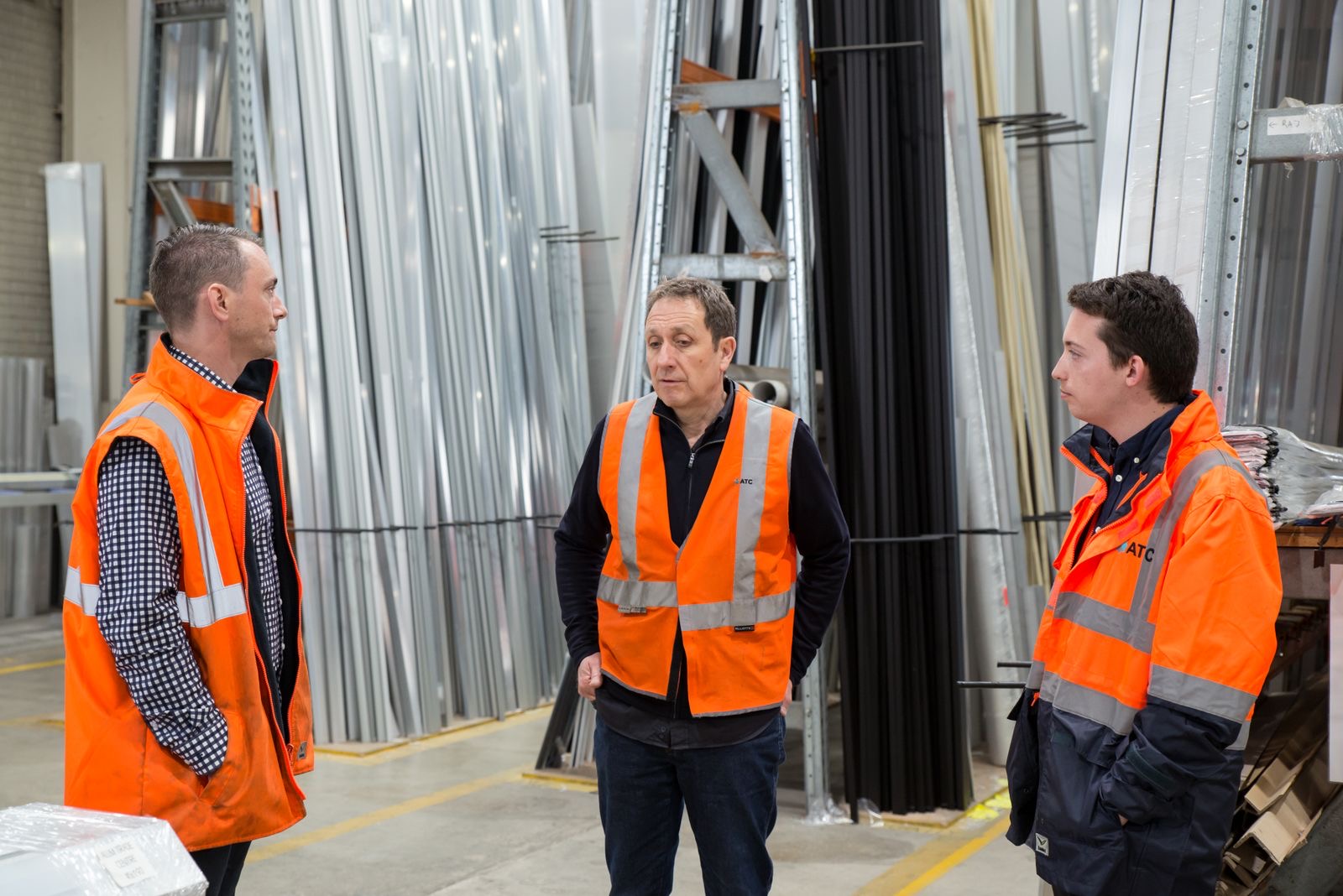 Workers in hi-vis vests talking together on the warehouse floor