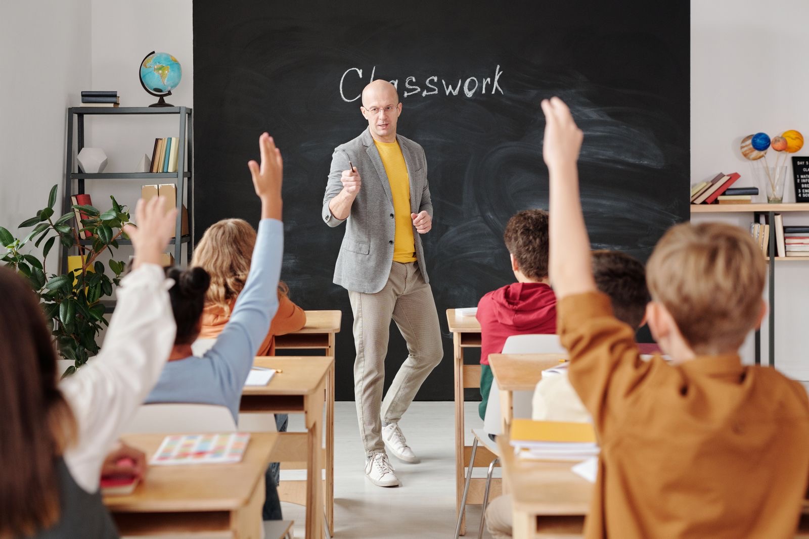 Teacher leading a class as students raise their hands